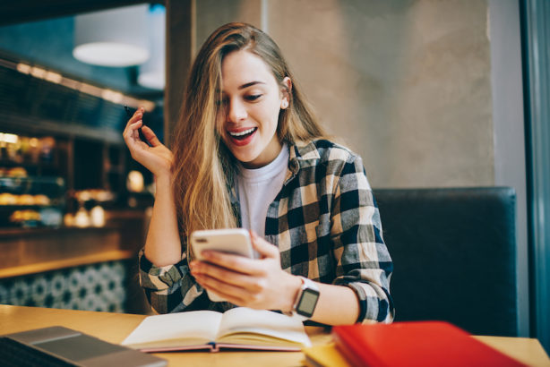 Wonder amazed hipster girl received text message on mobile phone about upcoming discounts, surprised female student chatting with friends and reading schocked news during studying at cafeteria